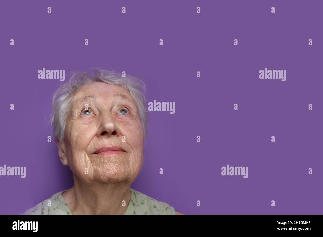 Smiling senior woman on lilac studio background. Hope and dreams concept Stock Photo