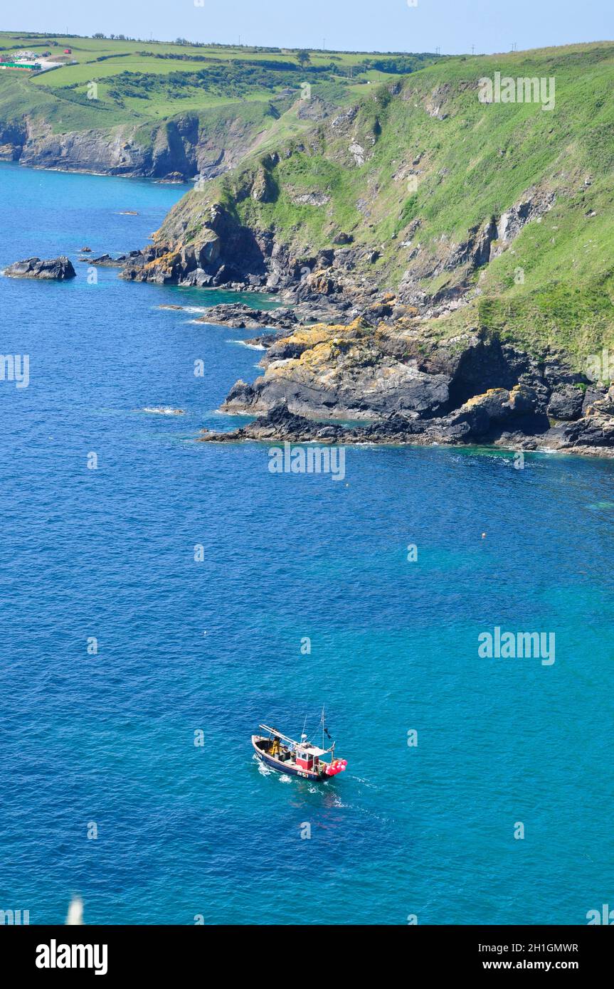 Coastal view walking from Cadgwith to Lizard point with fishing boat in foreground. Lizard Peninsula, Cornwall,UK Stock Photo