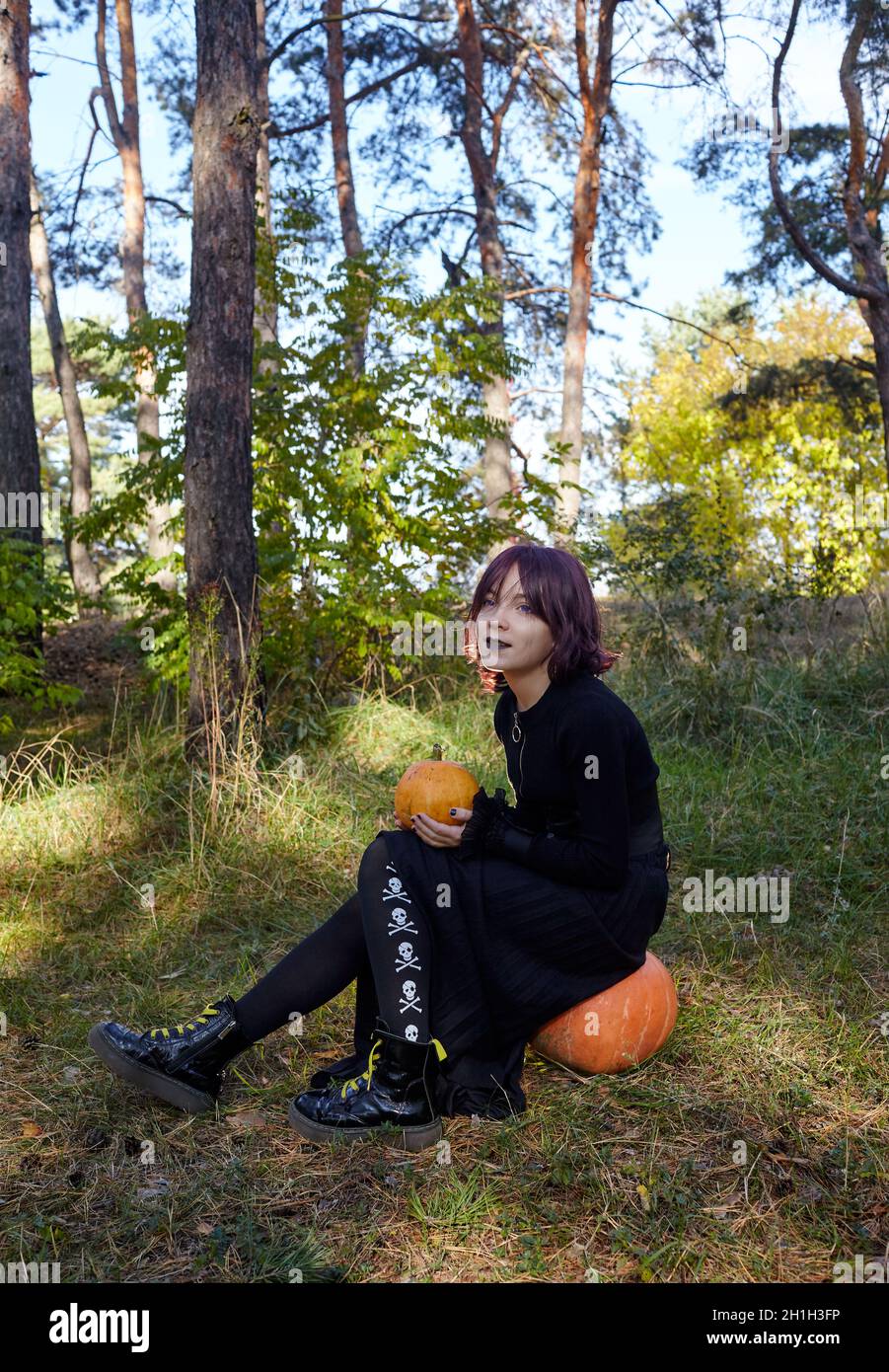 Teenager girl in witch costume posing in autumn forest. Funny kid in carnival costume at Halloween trick or treat. Happy Halloween! Stock Photo