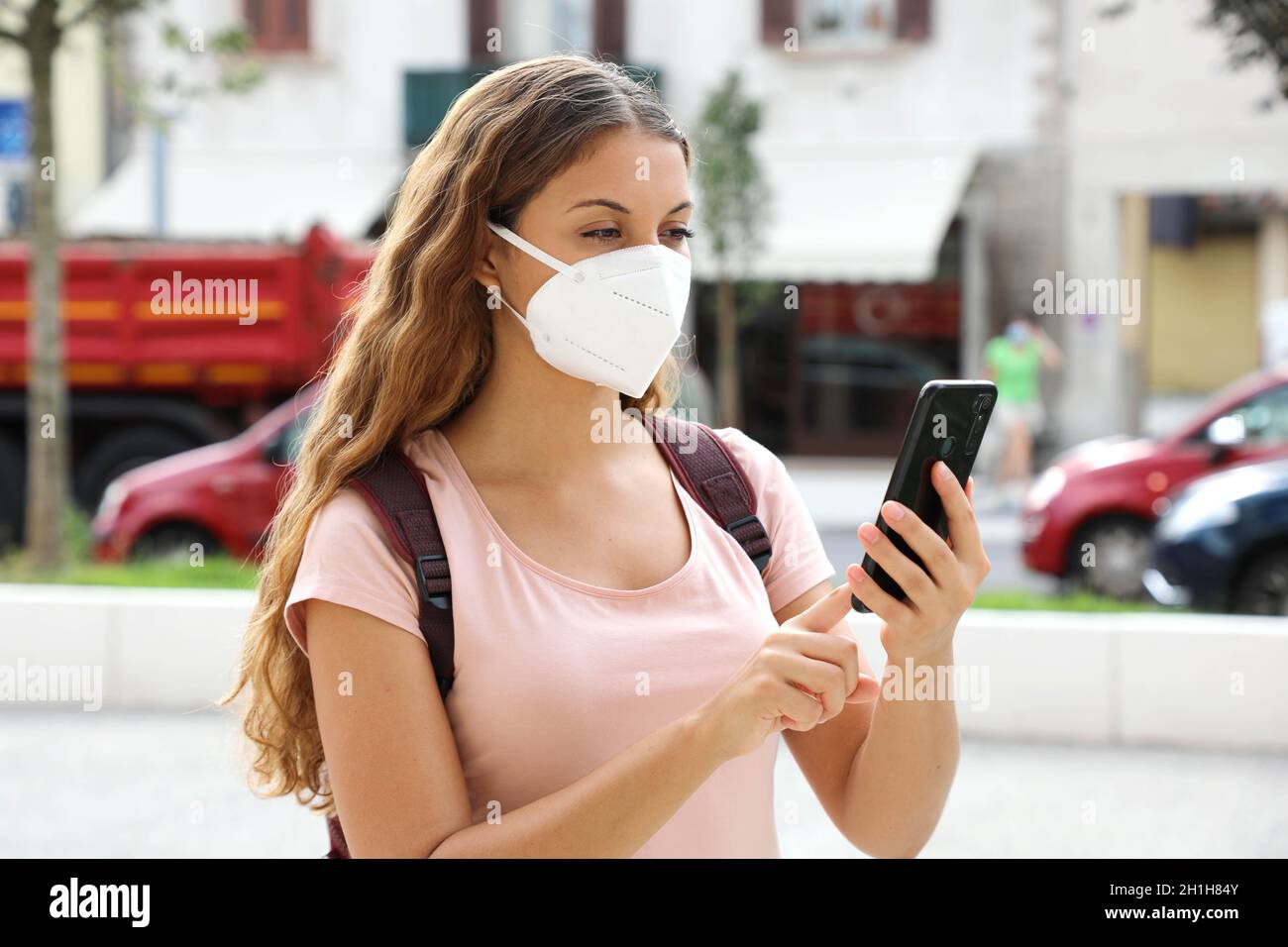 Brazilian woman with smart phone wearing face protective mask in the street Stock Photo