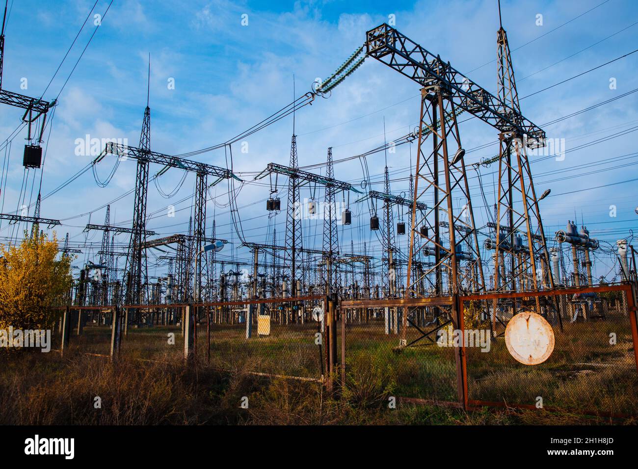 Electrical pylons and high voltage power lines are behind a barbed wire fence. Stock Photo