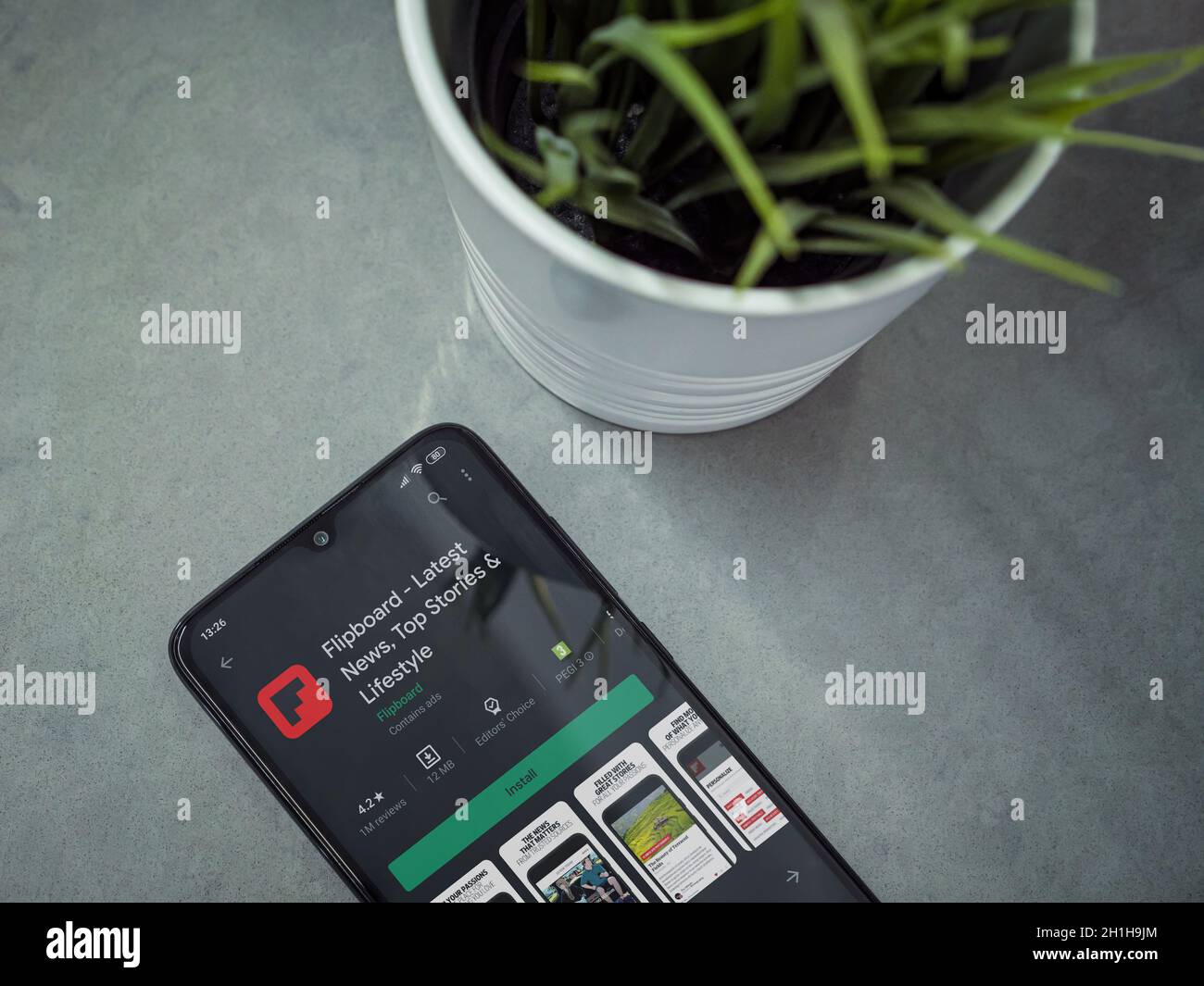 Lod, Israel - July 8, 2020: Modern minimalist office workspace with black mobile smartphone with Flipboard app play store page on marble background. T Stock Photo