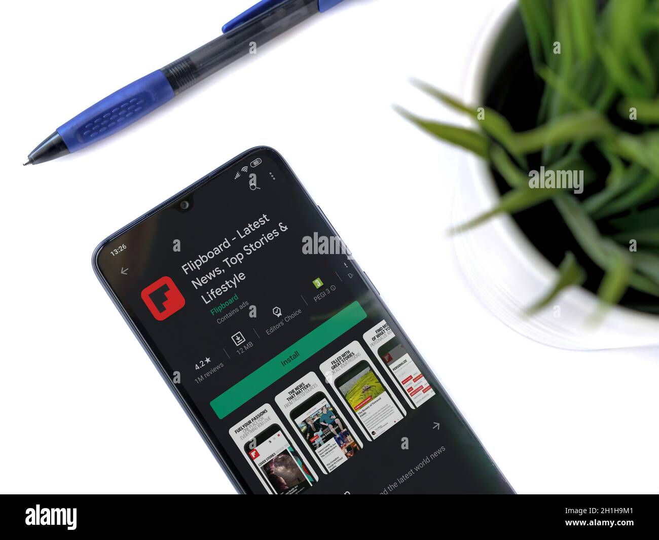 Lod, Israel - July 8, 2020: Modern minimalist office workspace with black mobile smartphone with Flipboard app play store page on white background. To Stock Photo
