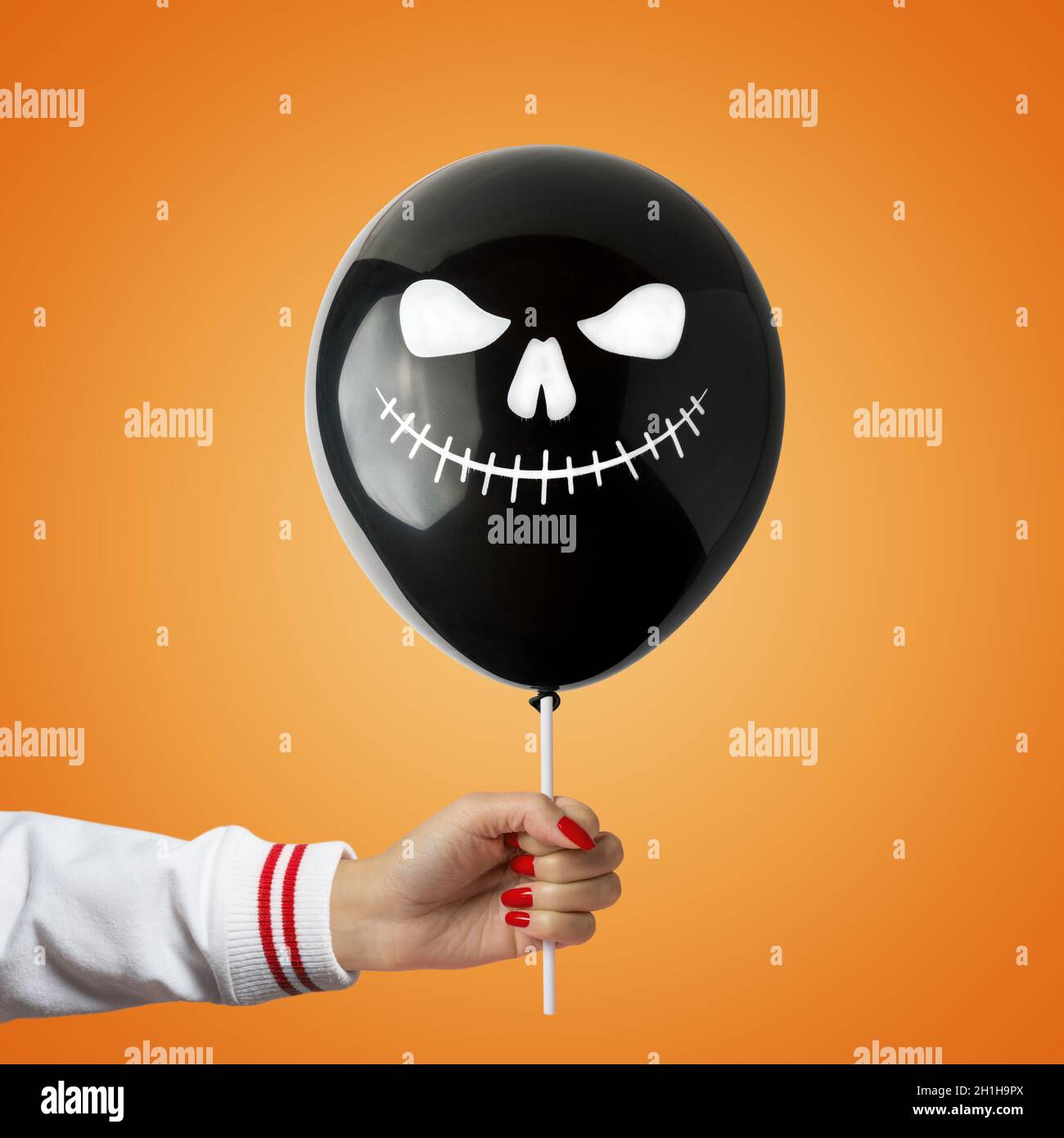Black Halloween balloon in hand on bright background. Minimal holiday concept. Stock Photo