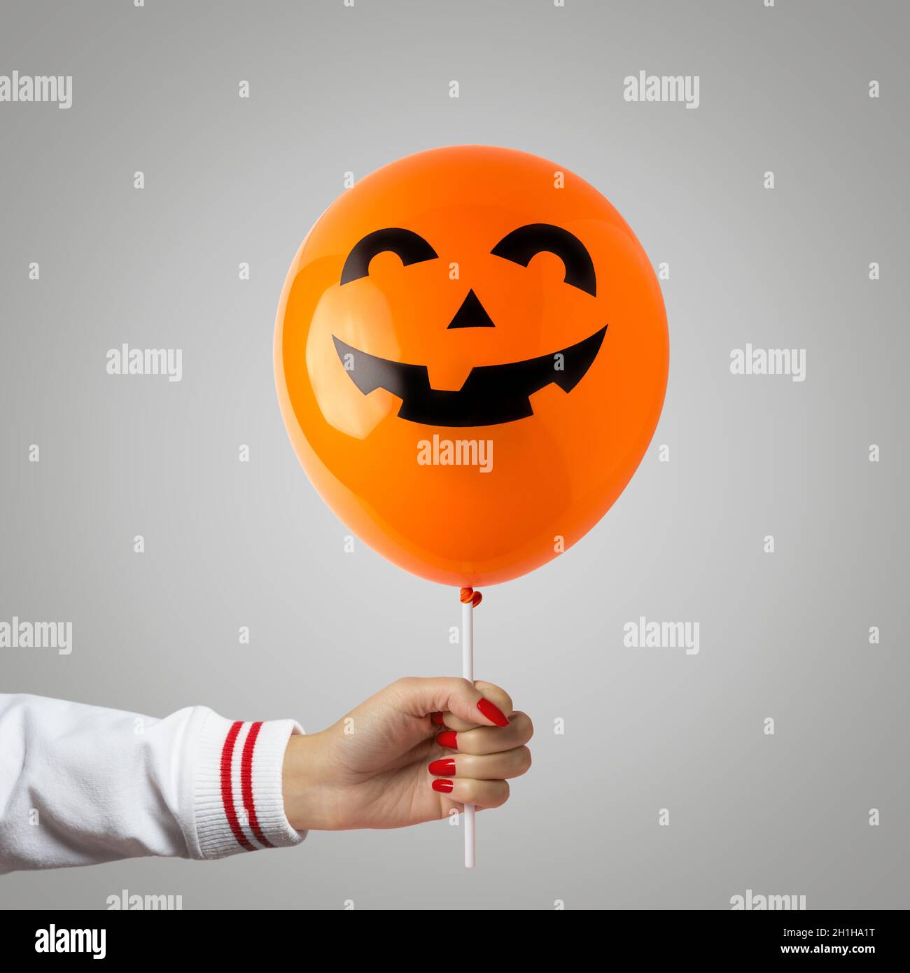 Halloween balloon in hand on bright background. Minimal holiday concept. Stock Photo