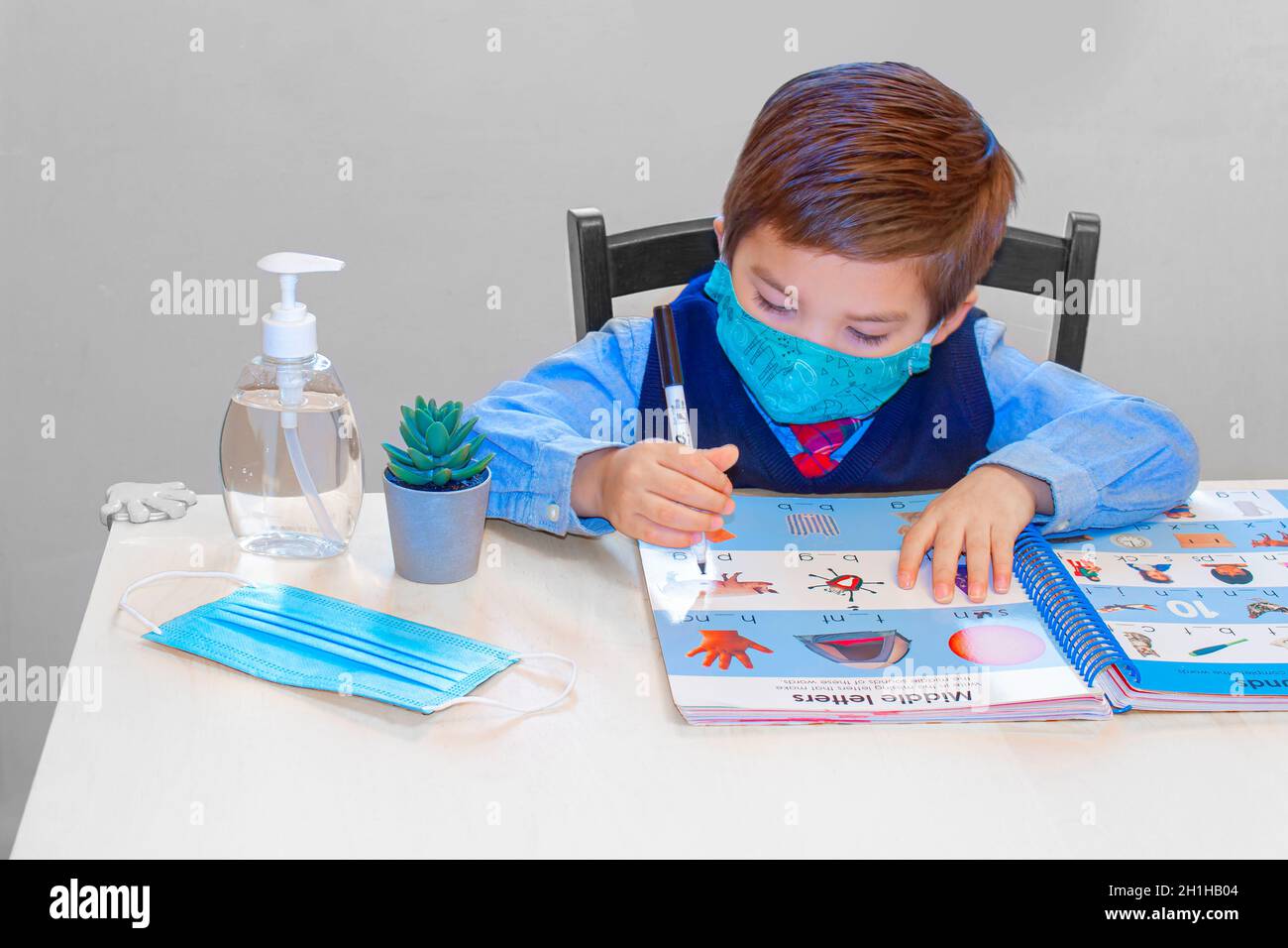 Calgary, Alberta, Canada. Sep 6, 2020. A kinder garden, pre-school student learning with an activity work book with a face mask and hand sanitizer on Stock Photo