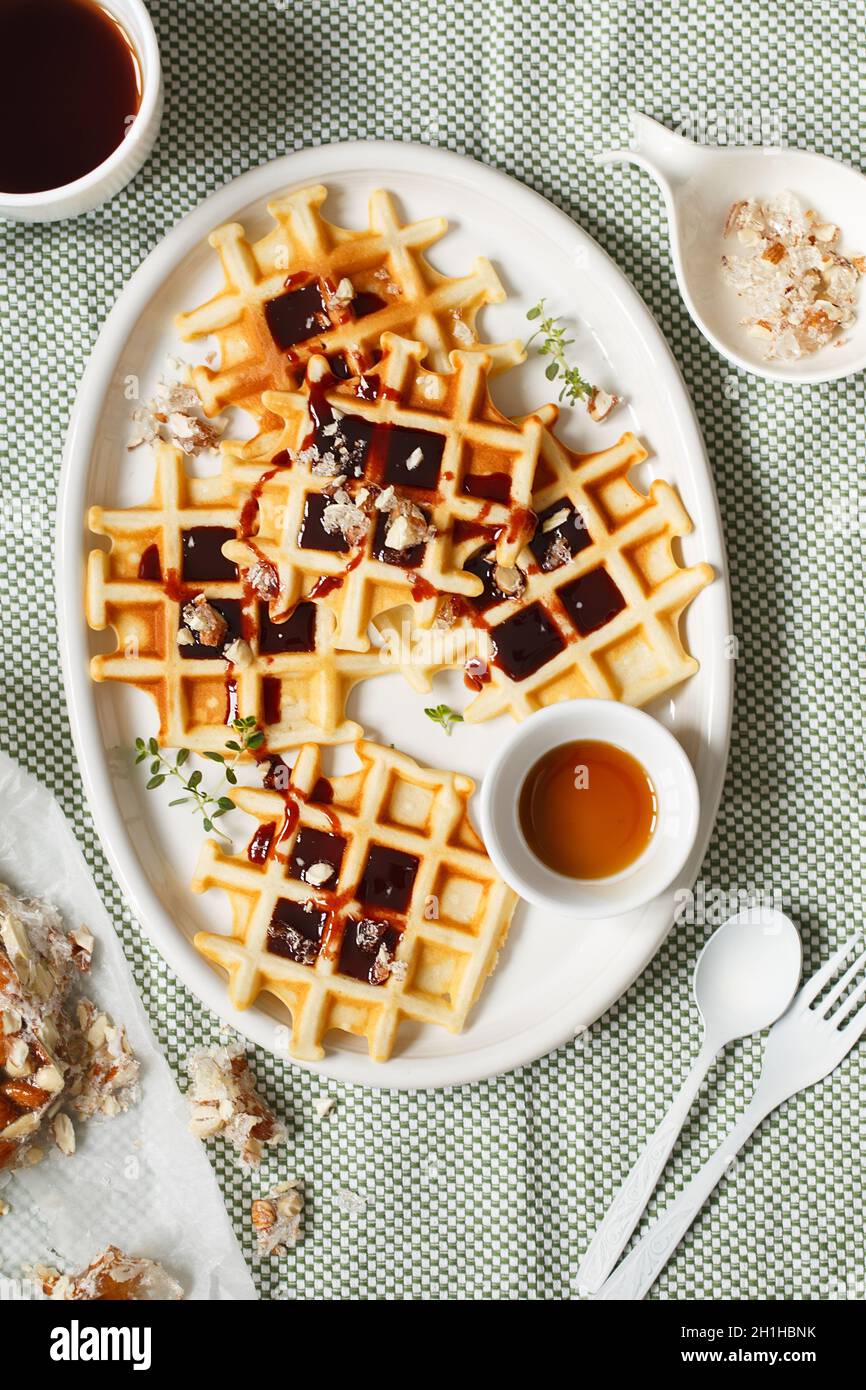 https://c8.alamy.com/comp/2H1HBNK/belgian-or-brussels-waffles-with-date-syrup-or-jam-and-candied-roasted-nuts-homemade-waffles-in-a-white-oval-plate-on-the-kitchen-table-traditional-2H1HBNK.jpg