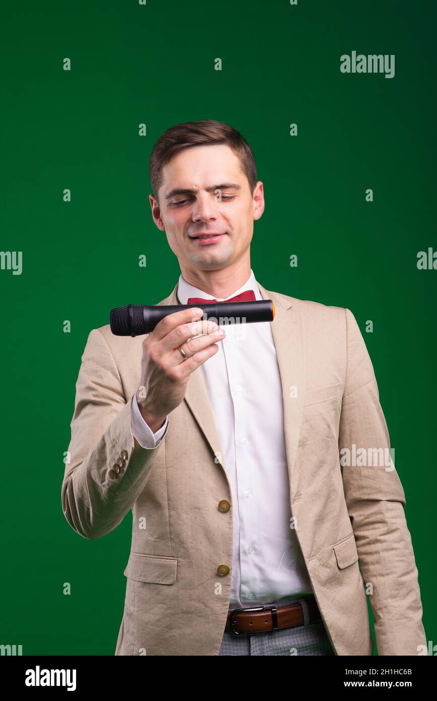 Portrait of male announcer holding microphone, isolated on green, white ...