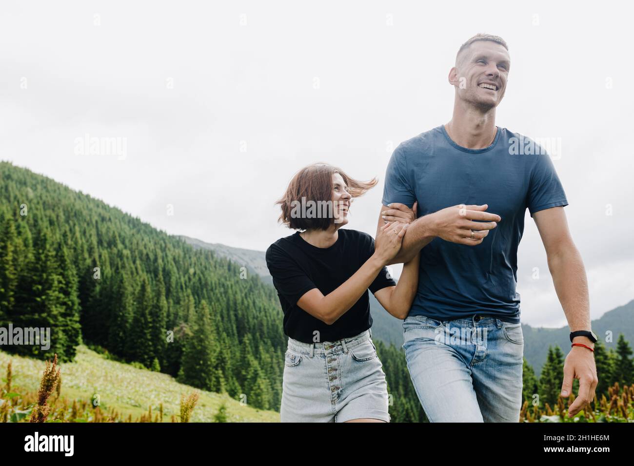 Tourists in love walk on the top of the hill and smile Stock Photo