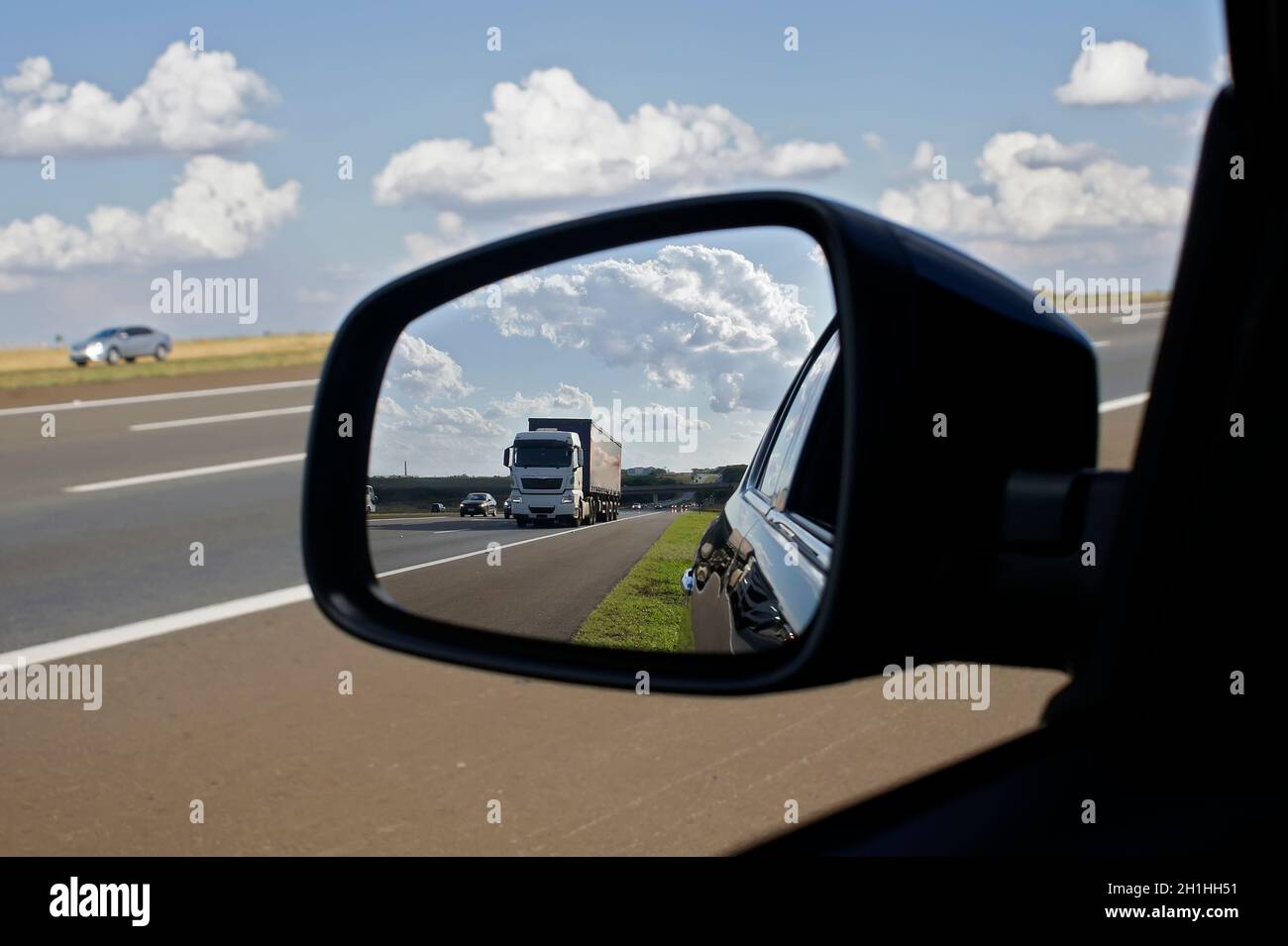 Truck on a highway seen in the rear view mirror on a summer day. Stock Photo