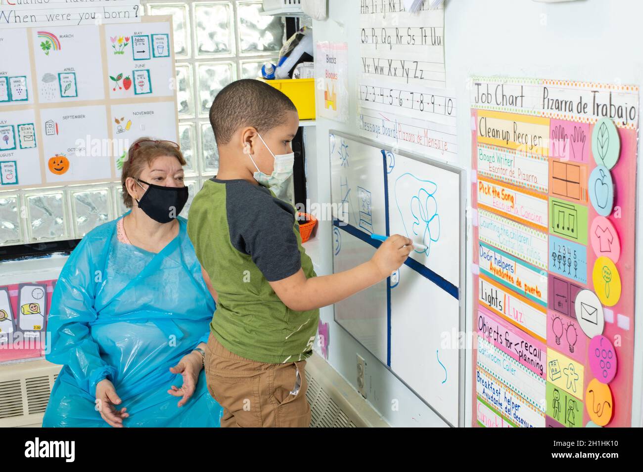 Education Preschool 4-5 year olds morning meeting female teacher observes boy drawing on dry erase board Stock Photo