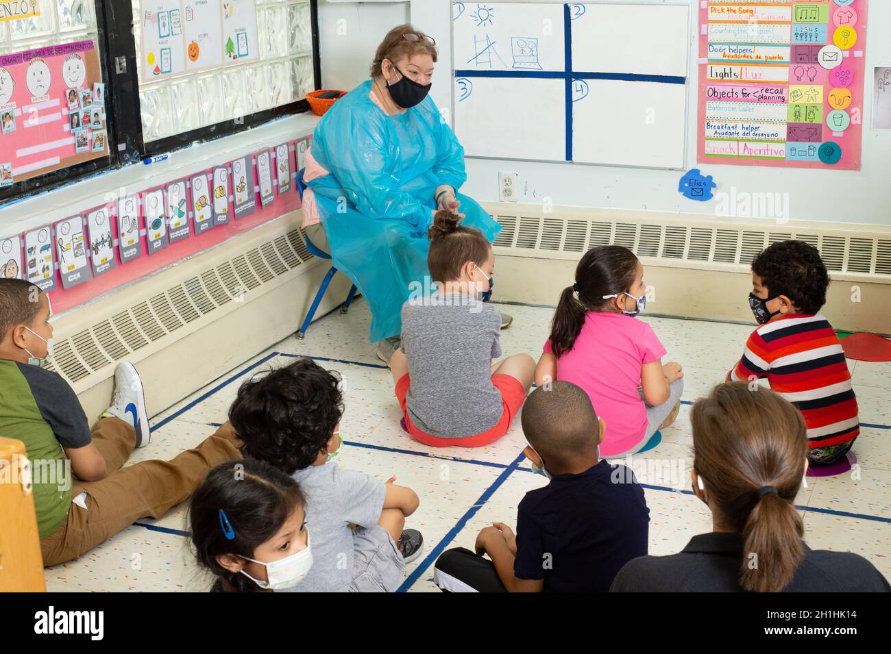 Education Preschool 4-5 year olds group with female teacher at morning meeting, wearing face masks to protect against Covid-19 infection Stock Photo