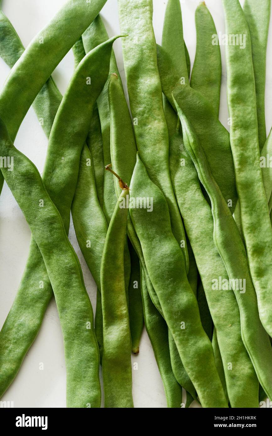 Romano flat green beans on white marble table top view. Healthy cooking ...