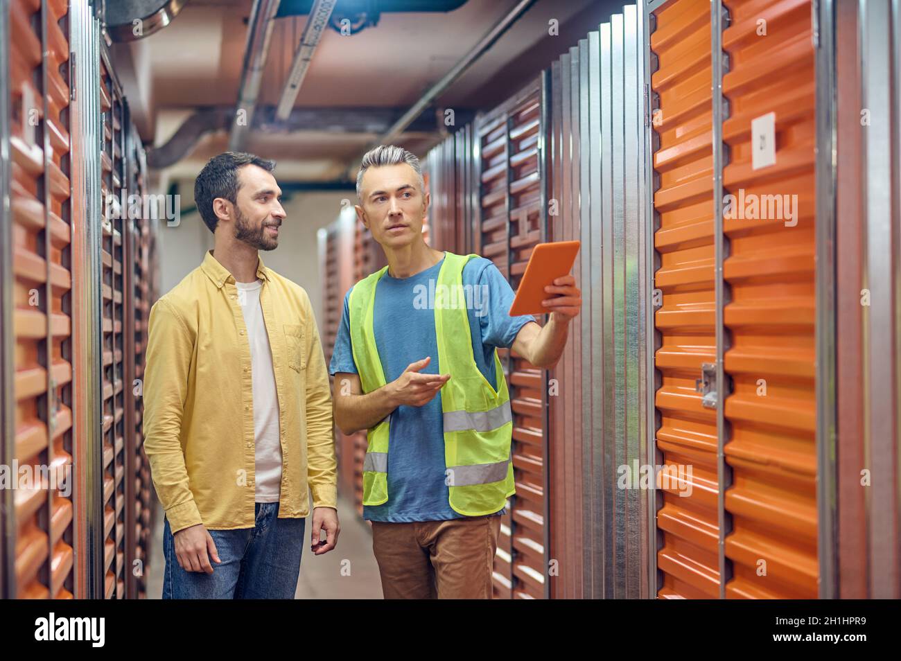 Smiling shopper and warehouse worker pointing to garage Stock Photo