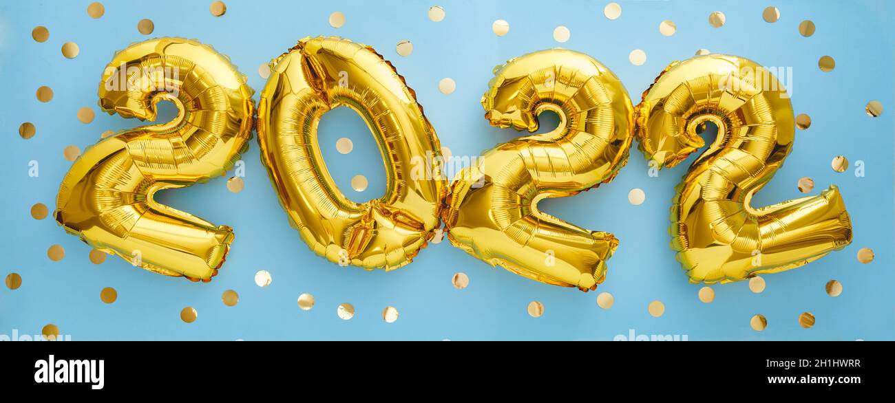 2022 year gold balloons with confetti on blue wall background. Happy New year 2022 eve celebration Stock Photo