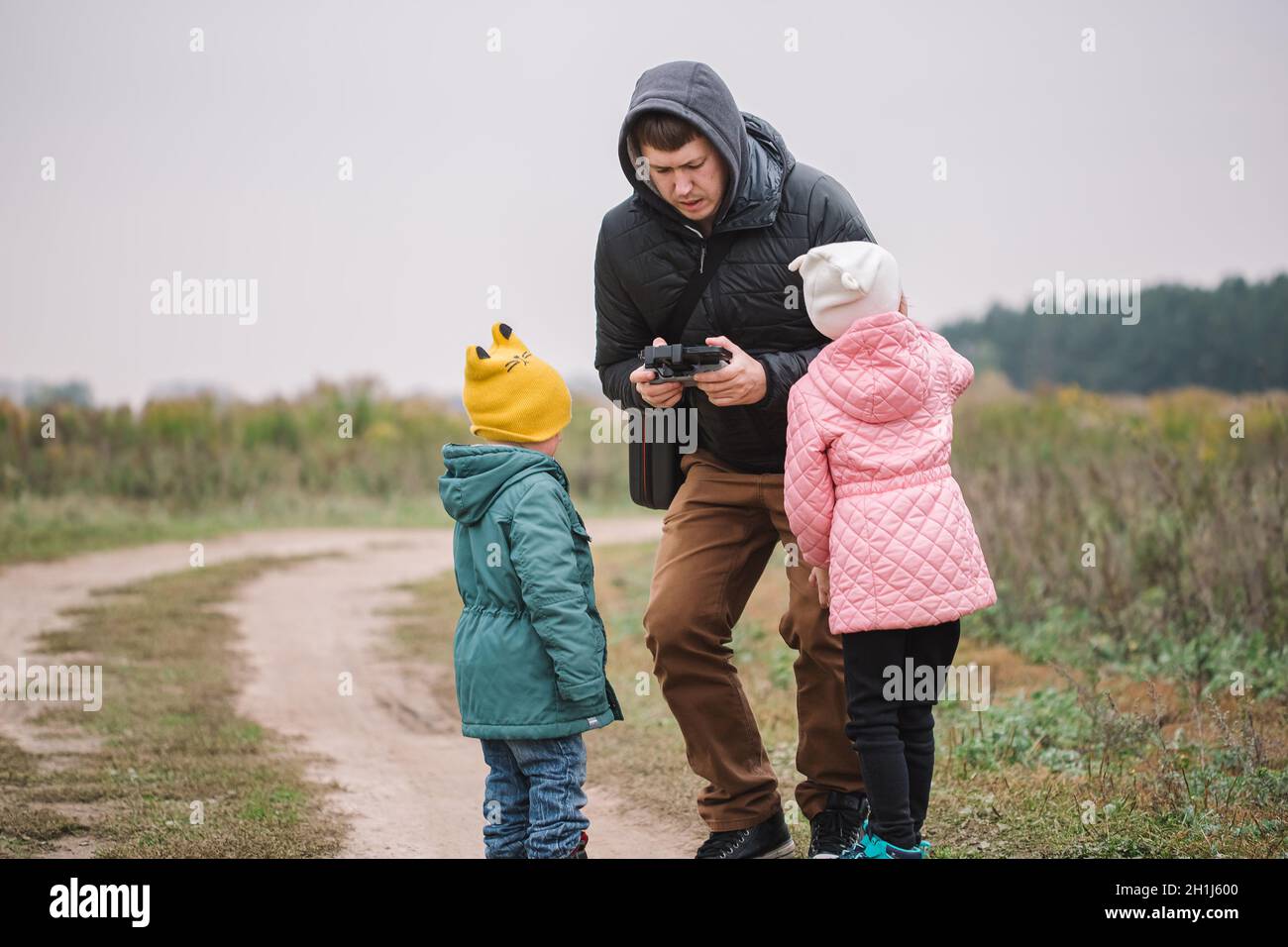 Happy family with two kids playing with drone in the field autumn time ...