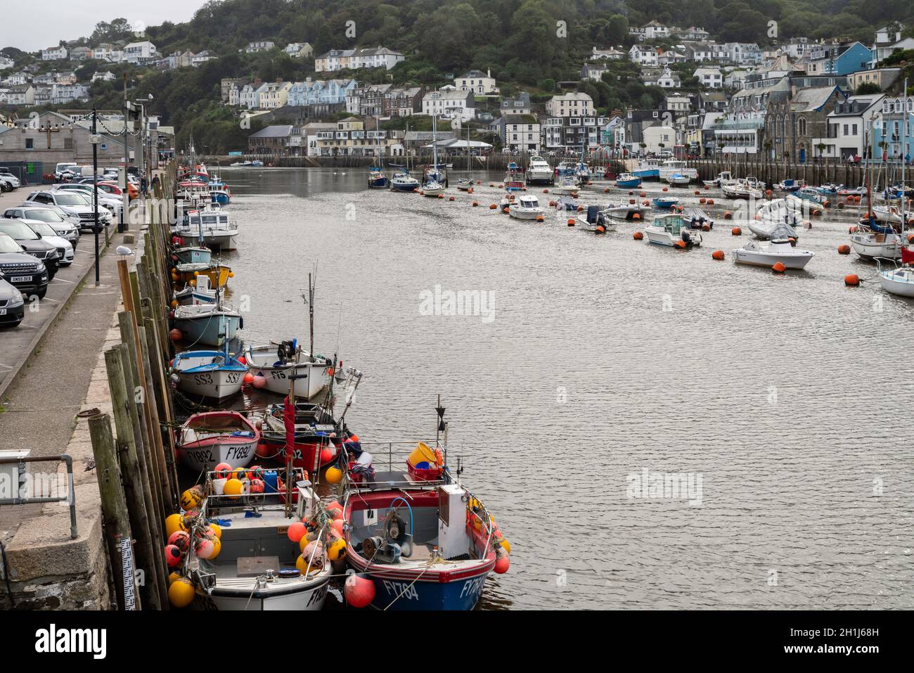 Fishing boats moored along the harbour wall in Looe, Cornwall. A working harbour popular with visitors. Stock Photo