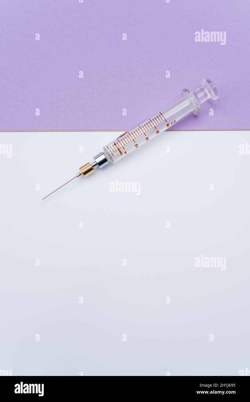 isolated sterilized glass injection syringe on a lilac paper background ...