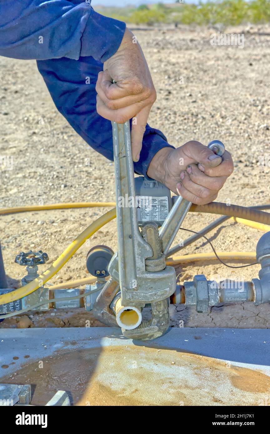 A plumber using pipe wrenches to fix a problem with a water Well in Arizona. Stock Photo