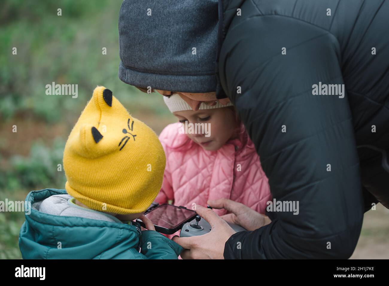 Happy family with two kids playing with drone in the field autumn time. Stock Photo