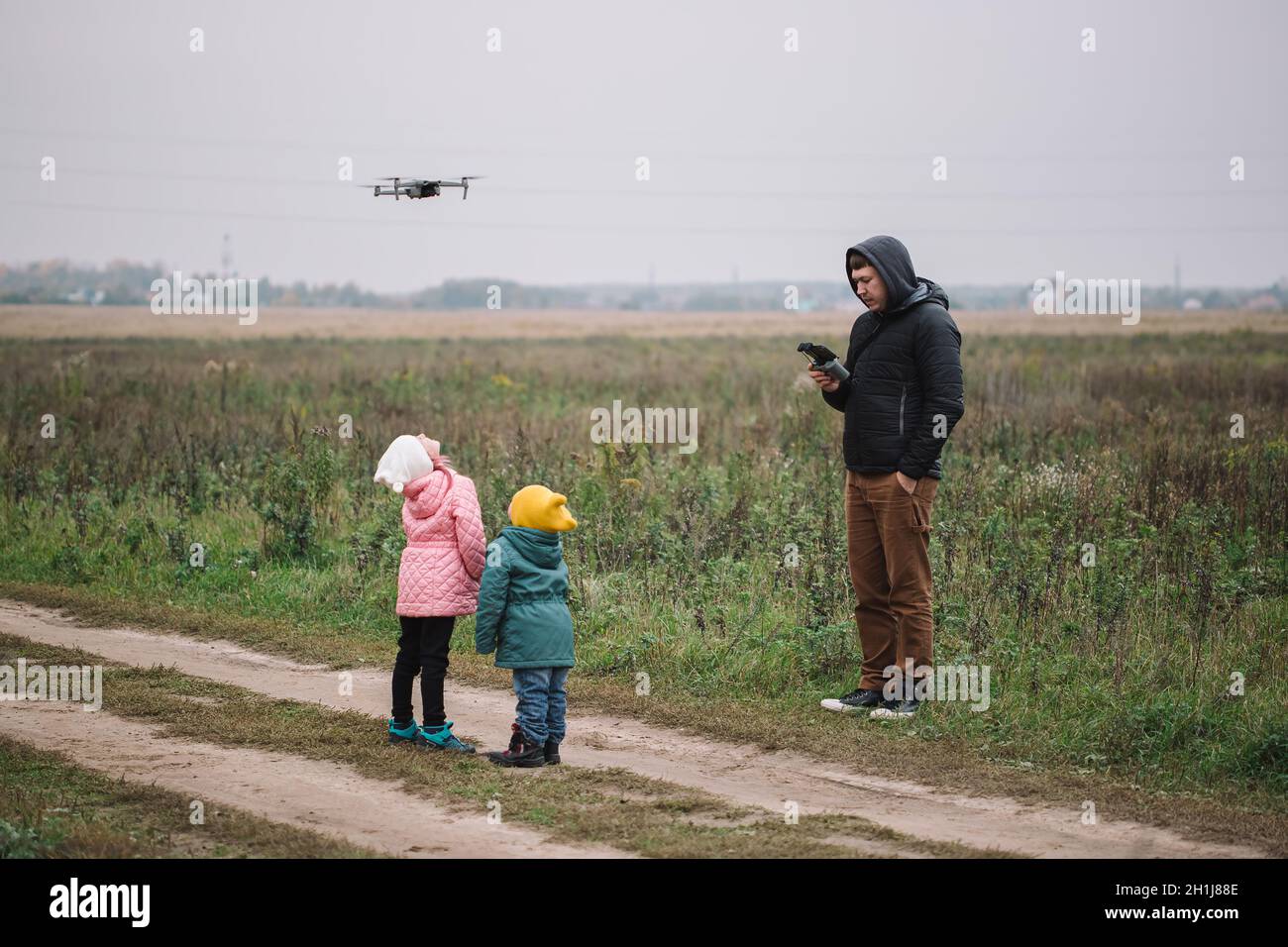 Happy family with two kids playing with drone in the field autumn time ...