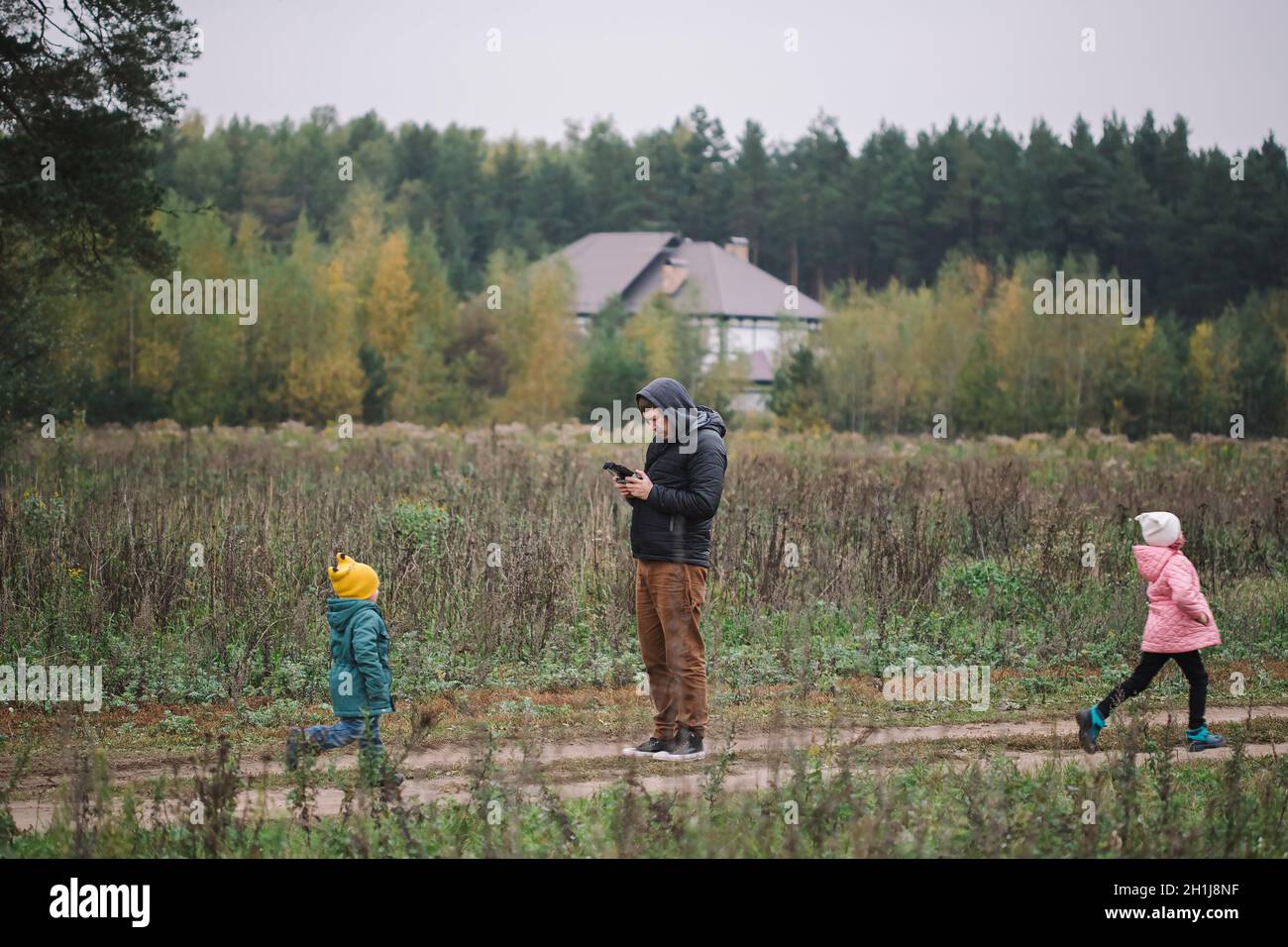 Happy family with two kids playing with drone in the field autumn time ...