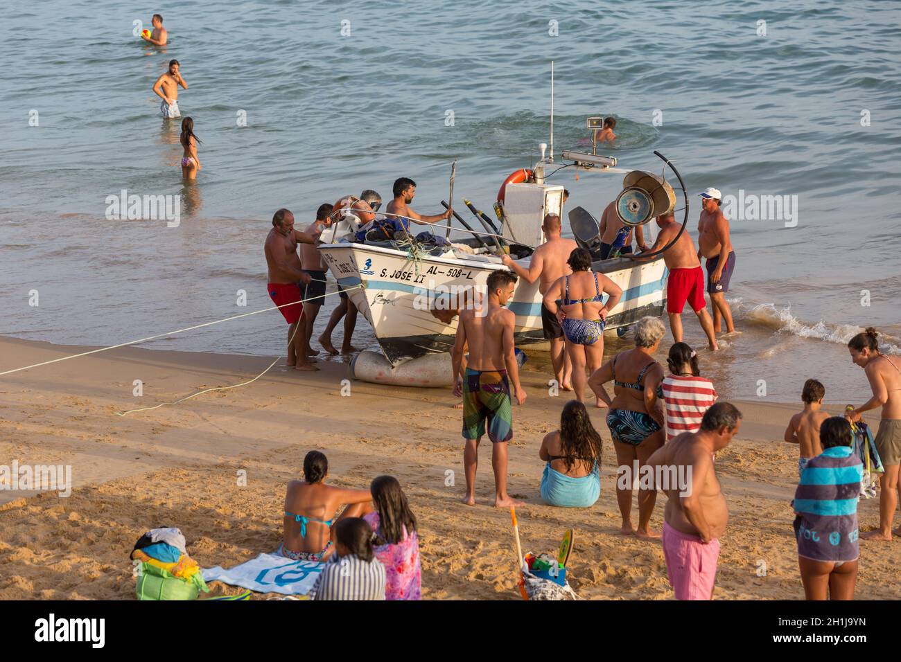 ALBUFEIRA, PORTUGAL - AUGUST 24, 2017: The last fishing ship of Olhos de Agua in Albufeira. The Tourists help the fisherman taking the boat in to the Stock Photo