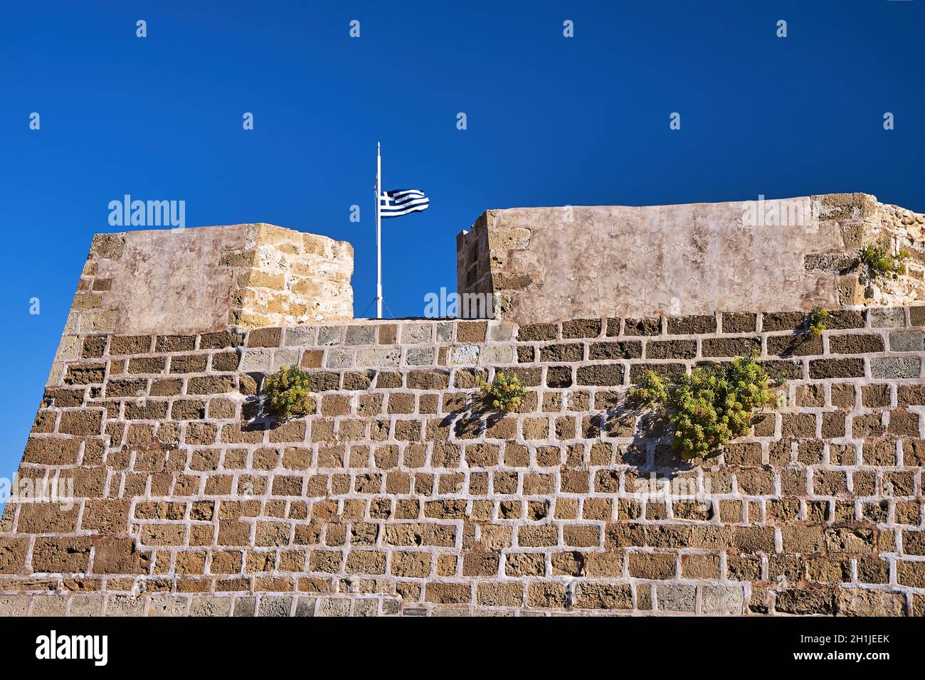 Fragment of the wall of the Venetian fortress and the Greek flag in the city of Chania on the island of Crete Stock Photo