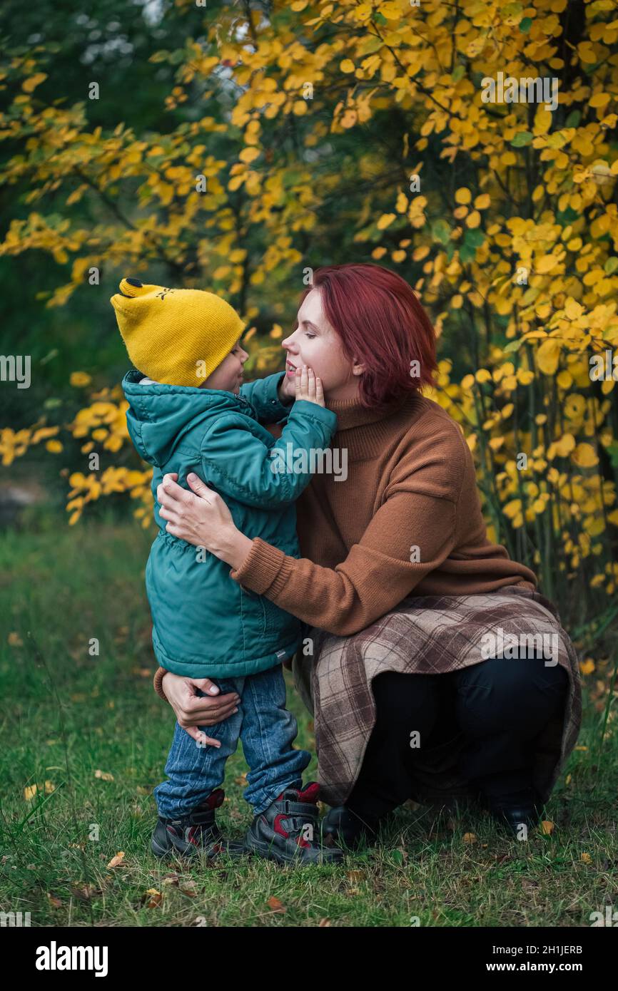 Little caucasian boy and his mother against yellow autumn forest. Stock Photo