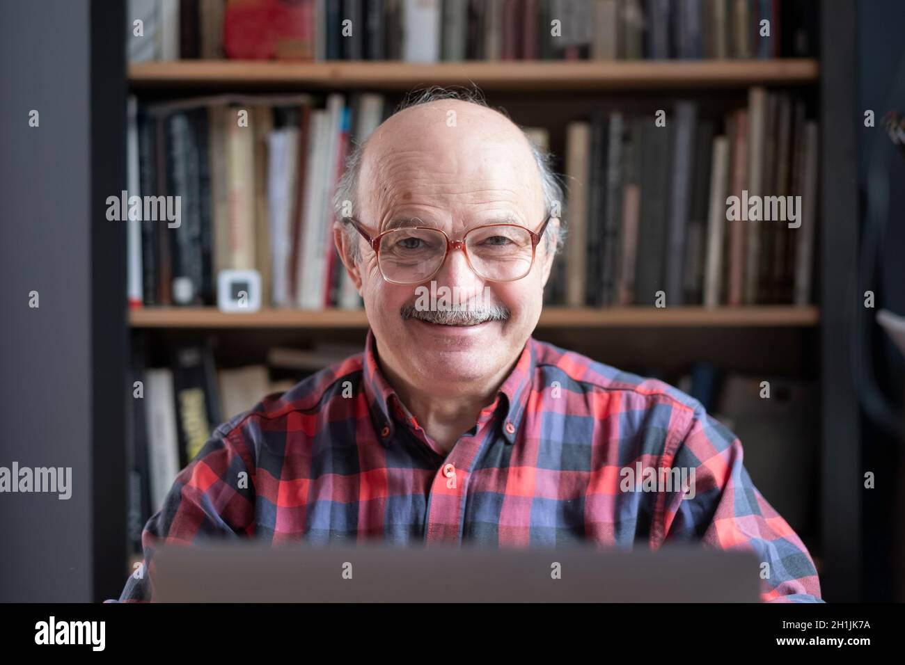 Senior man at home in front of laptop computer Stock Photo