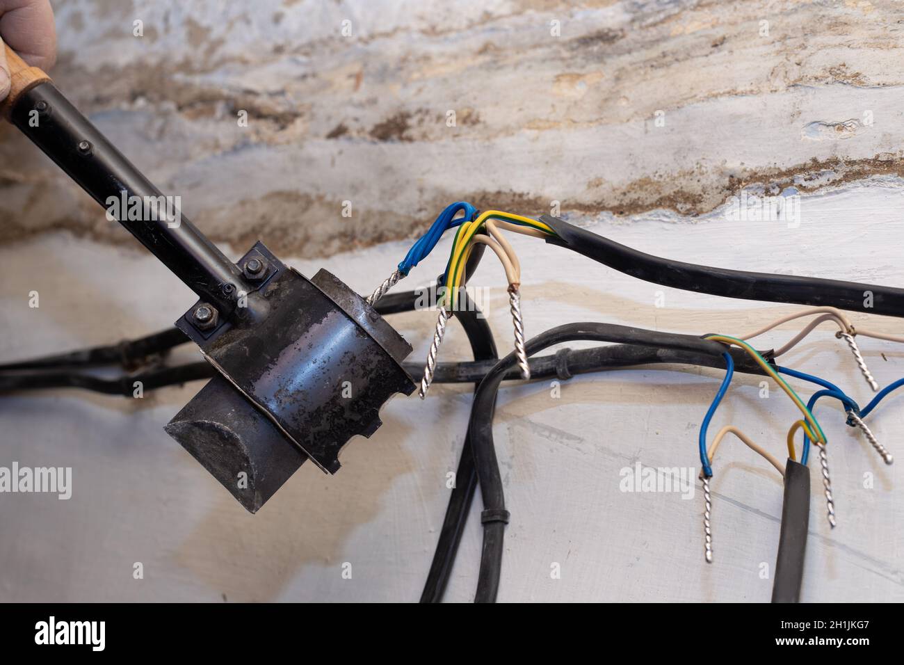 An electrician solders twisted electrical wires in a house under