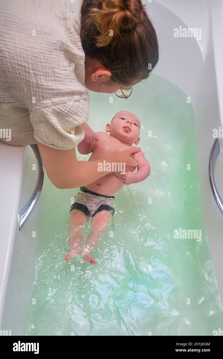 Mom and son are engaged in infant swimming in the home bathroom. A