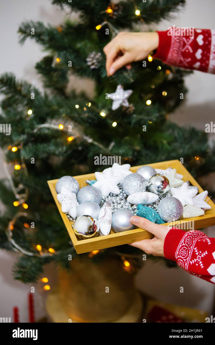 Happy Girl Holds A Tray With Christmas Toys In Her Hands And Decorates The Christmas Tree At Home For Christmas, 2022 Year Of The Tiger Stock Photo - Alamy