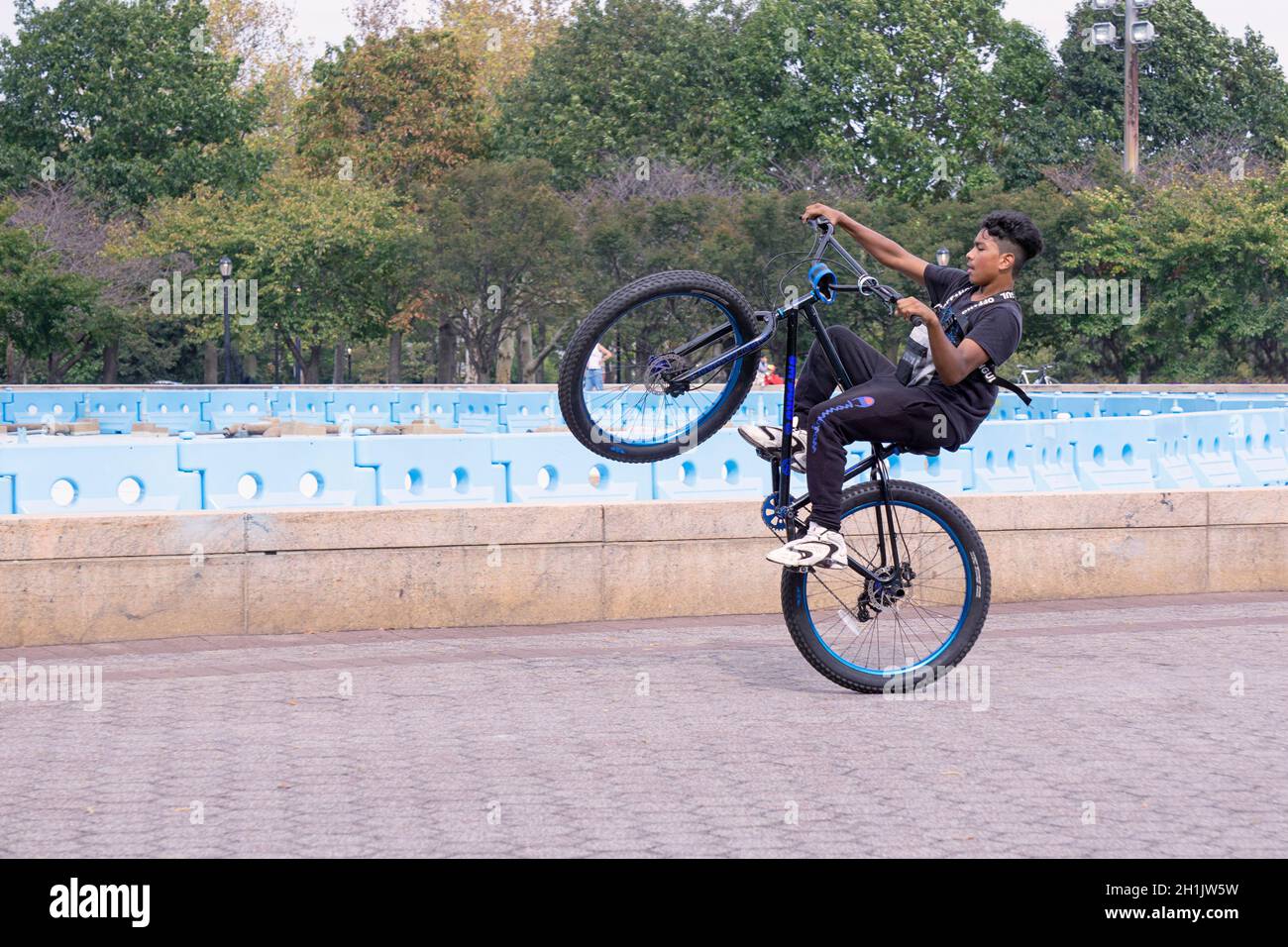 A teenage boy does wheelies on his bike while riding laps around the