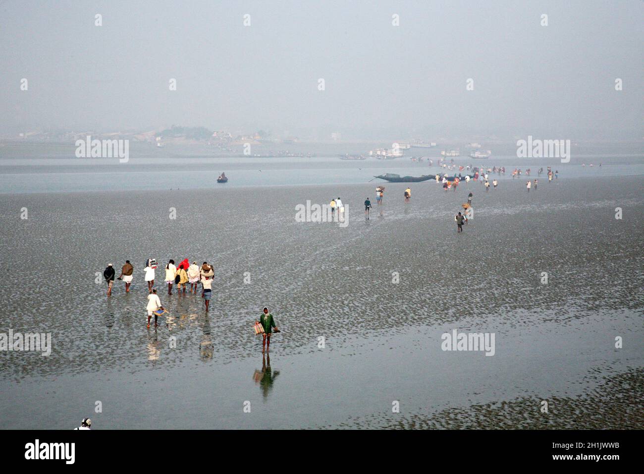 During low tide the water in the river Matla falls so low that people walk to the other shore in Canning Town, India Stock Photo