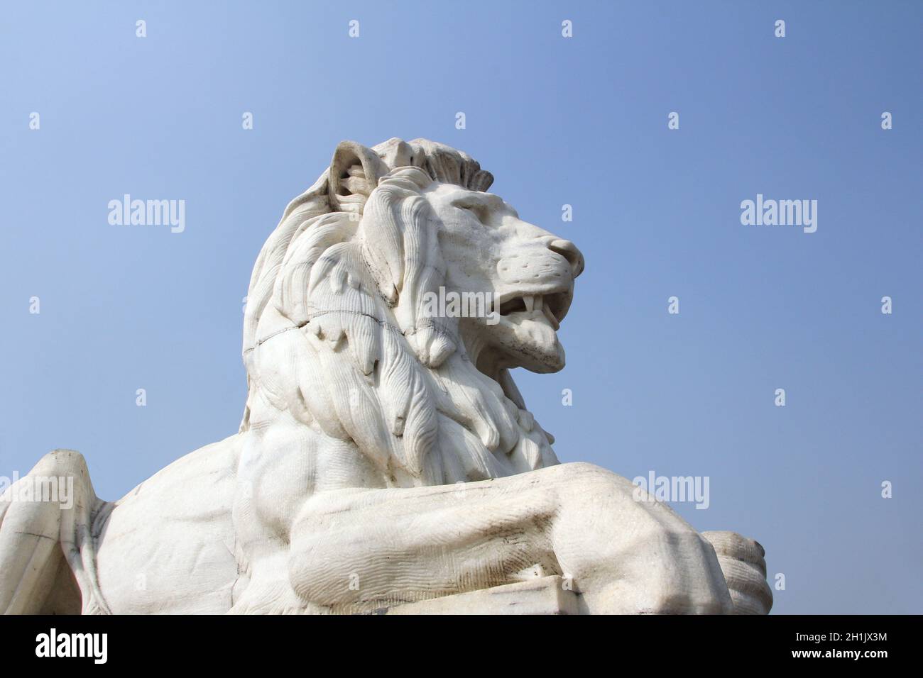 Antique Lion Statue in sky background at Victoria Memorial Gate, Kolkata, India. Built with white Makrana Marbles using the European and the Indo-Isla Stock Photo