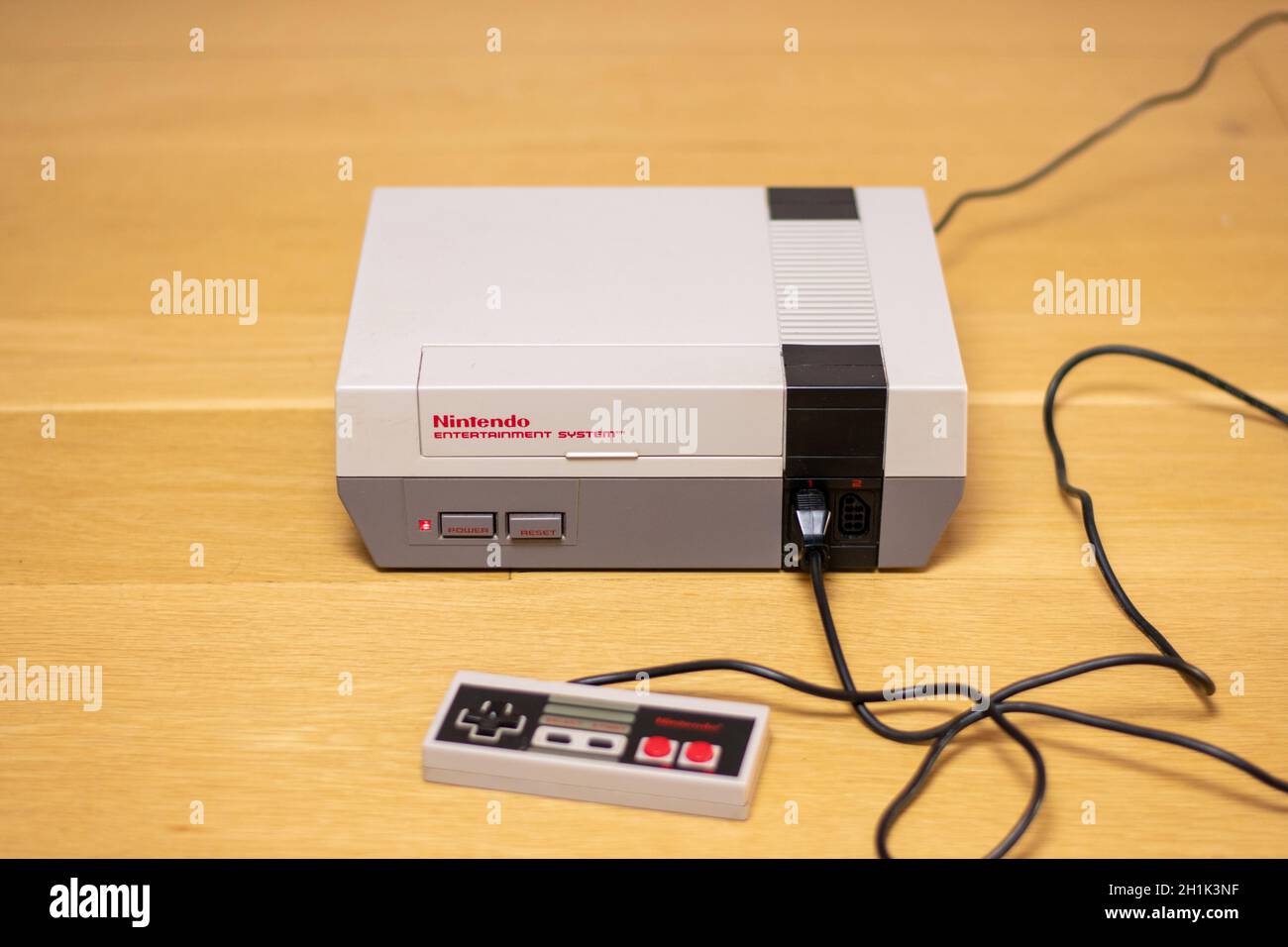 A Nintendo Entertainment System With a Controller Plugged In. The NES is a popular retro console. Stock Photo