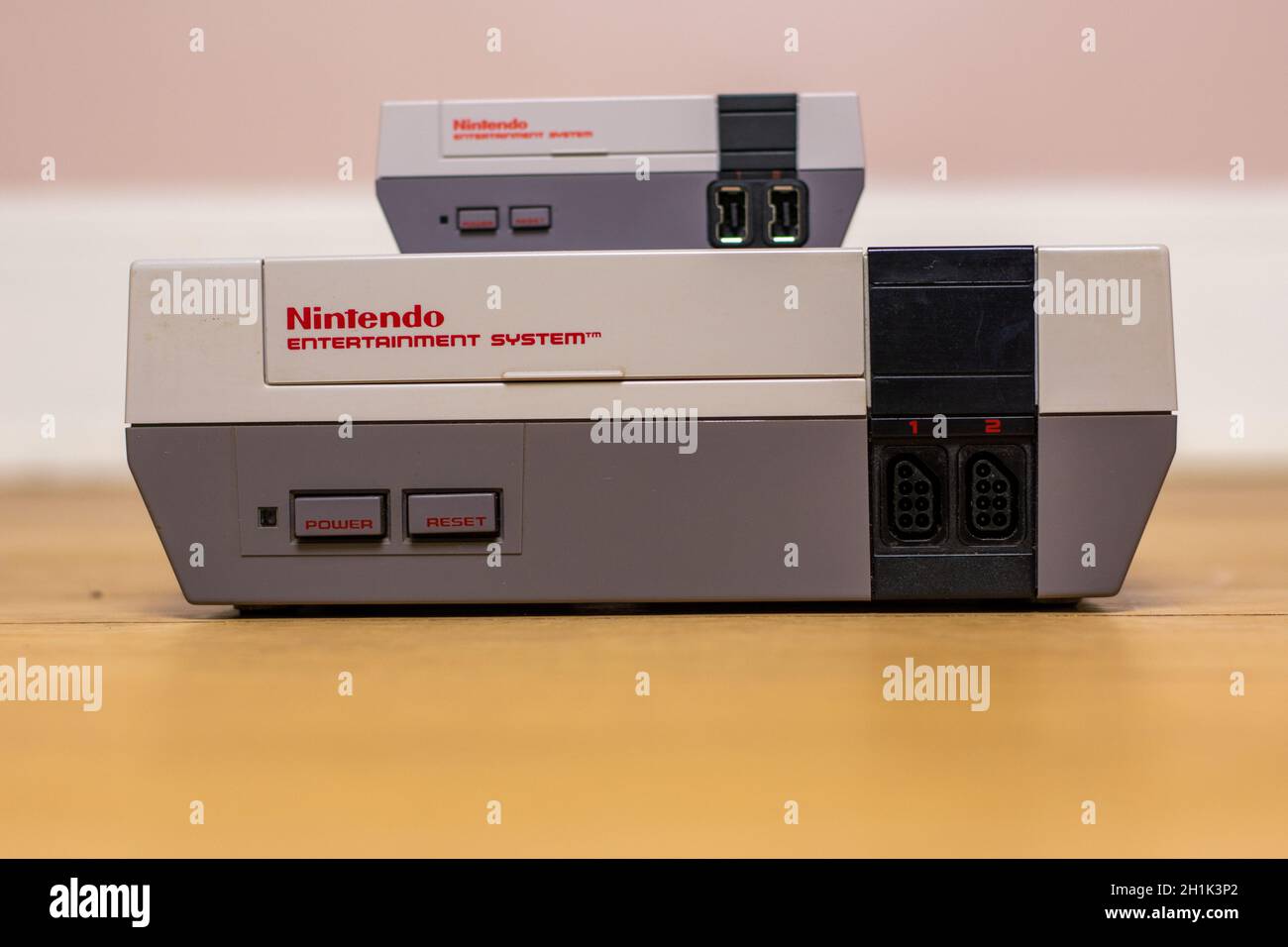 A Nintendo Entertainment System Classic Edition on Top of an Original Nintendo Entertainment System, on a wood floor. Comparison of the original NES a Stock Photo