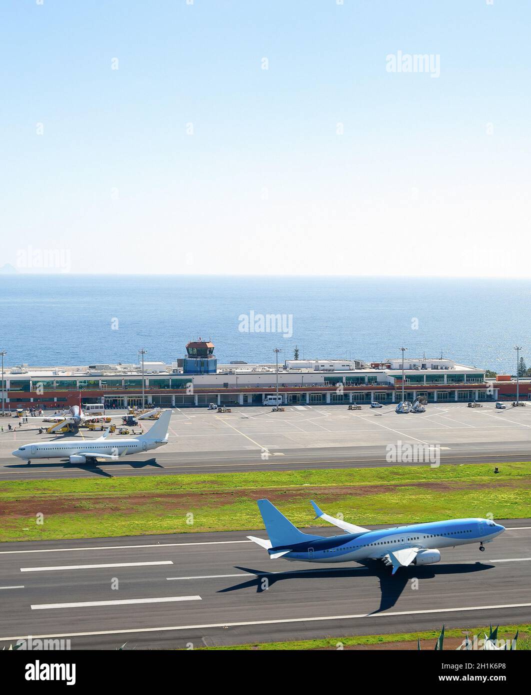 Aerial view of airplaine taking off runway at Madeira international airport, terminal building  in the background, Portugal Stock Photo