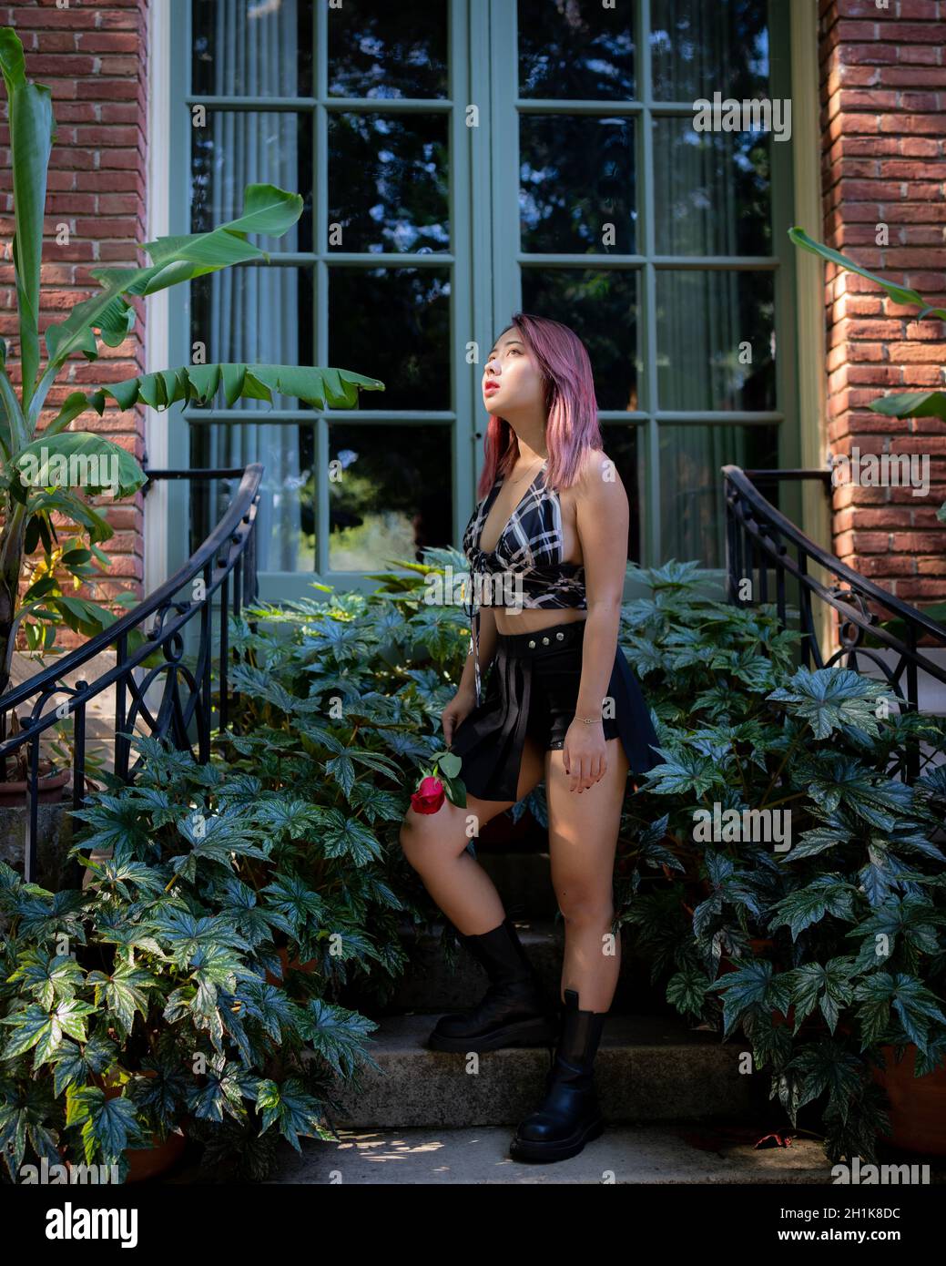 Young Asian Woman Holding a Rose in a Garden Setting Stock Photo