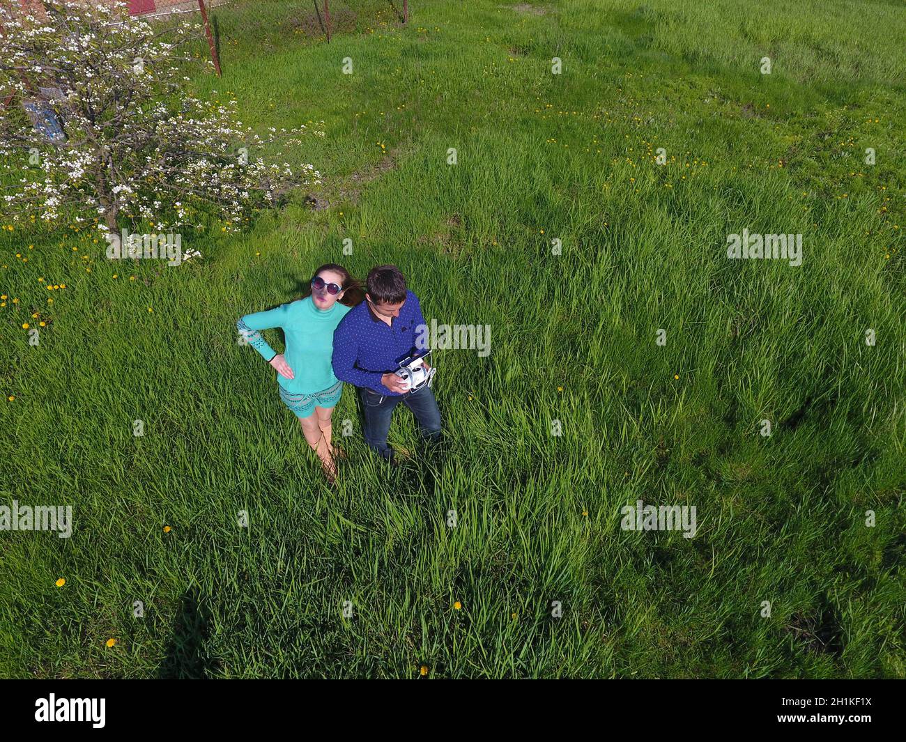 A man and a woman are photographed from a drone on a green clearing Stock Photo
