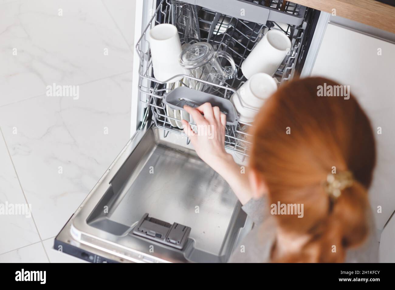 Housework young woman putting dishes in the dishwasher Stock Photo Alamy