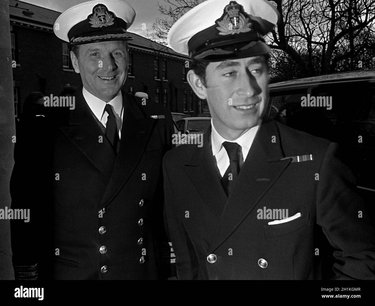 AJAXNETPHOTO. 12TH JANUARY, 1976. PORTSMOUTH, ENGLAND, - PRINCE STARTS COURSE - HRH PRINCE CHARLES IN ROYAL NAVY UNIFORM ARRIVING AT HMS VERNON TO BEGIN A 4 WEEK COMMANDING OFFICER TRAINING COURSE IS WELCOMED BY BASE COMMANDING OFFICER CAPTAIN G.TRISTE RN (LEFT). PHOTO;JONATHAN EASTLAND/AJAX REF:761201 18A Stock Photo