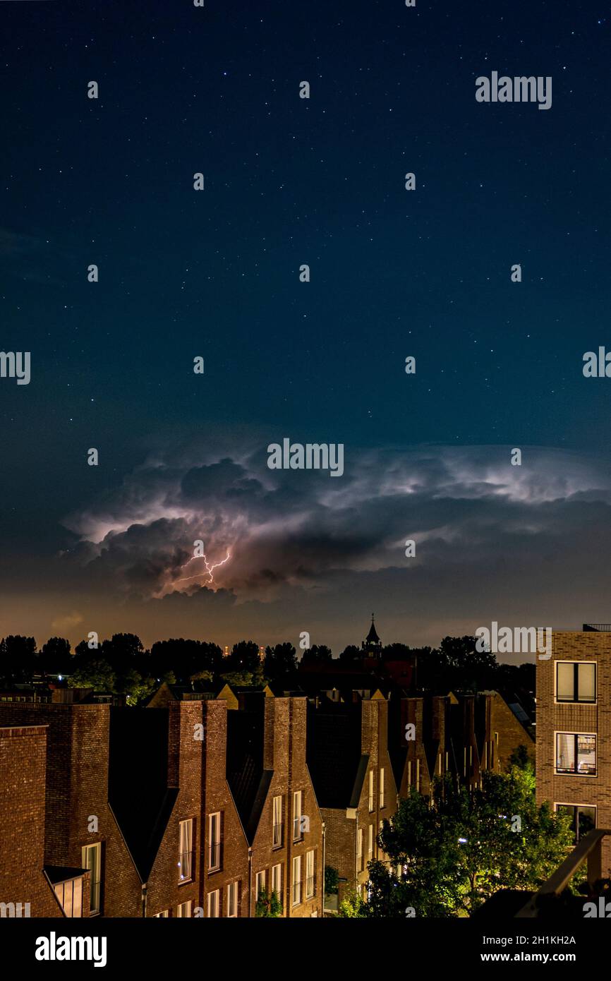 Stormy clouds in a dark night sky over the town Stock Photo