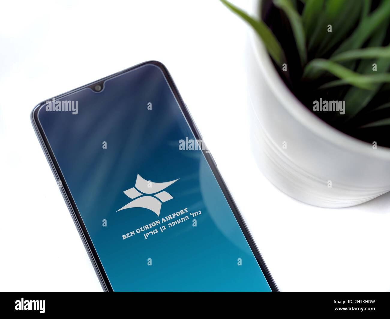 Lod, Israel - July 8, 2020: Modern minimalist office workspace with black mobile smartphone with Ben Gurion Airport app launch screen with logo on whi Stock Photo