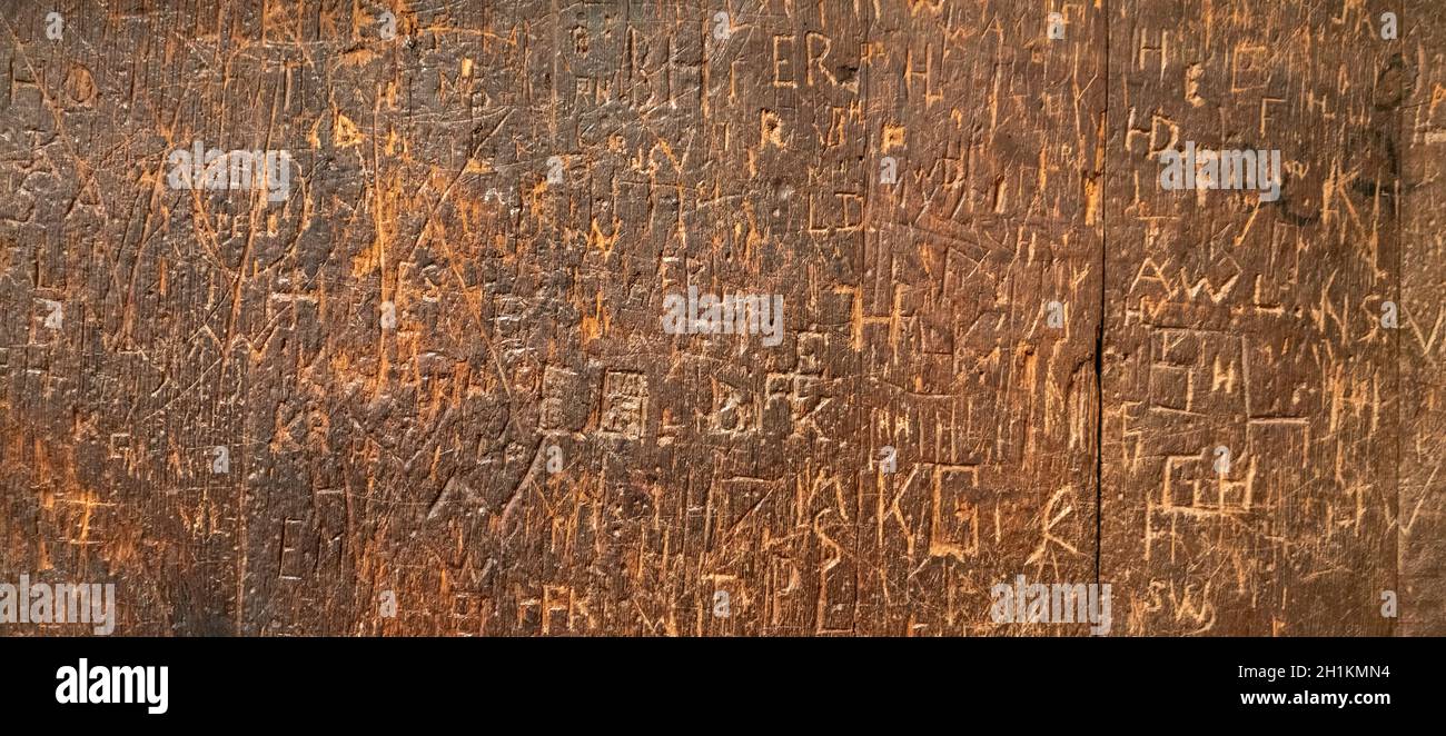 old wooden surface covered with lots of engraved graffiti tags Stock Photo