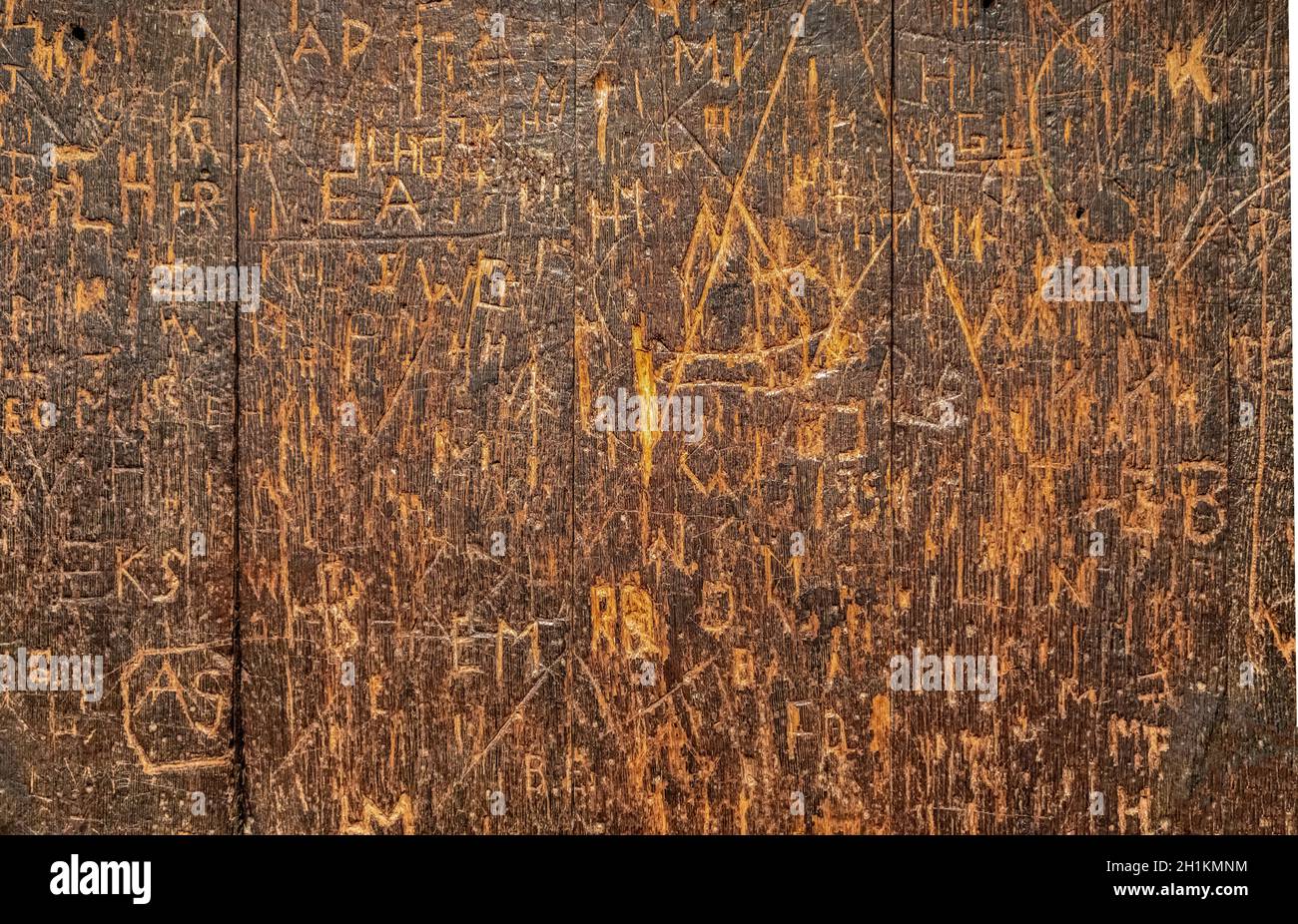 old wooden surface covered with lots of engraved graffiti tags Stock Photo