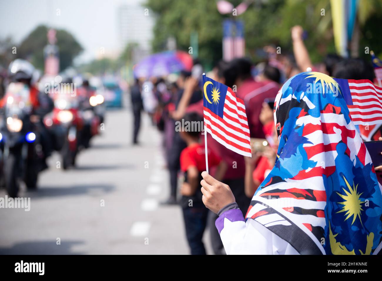 Butterworth, Kuala Lumpur/Malaysia - Aug 31 2019: A muslim girl hold Malaysian tudung and mask wave the Malaysia flag during independence day. Stock Photo