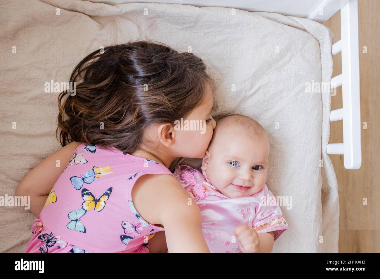 Little girl lying on bed lovingly and peacefully hugging and kissing