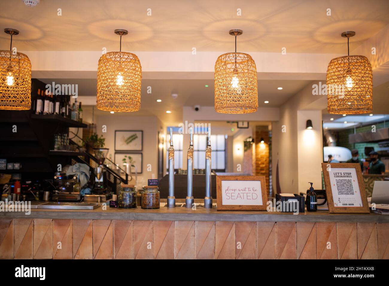 Picture of four handcrafted lamps hanging over a wooden counter with the interior of a vegan restaurant as background Stock Photo